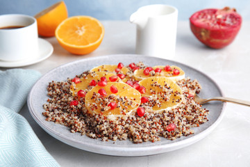 Plate of quinoa porridge with orange and pomegranate seeds served for breakfast on table