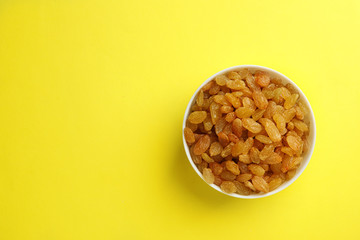 Bowl with raisins and space for text on color background, top view. Dried fruit as healthy snack