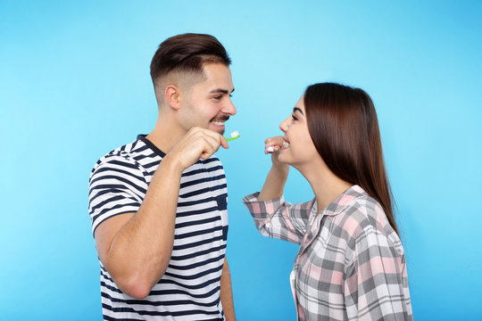 Happy couple brushing teeth on color background