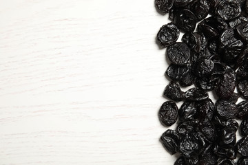 Dried plums on wooden background, top view with space for text. Healthy fruit