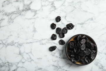 Plate of sweet dried plums on marble background, top view with space for text. Healthy fruit