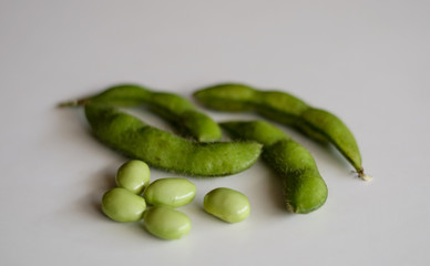 Young soy beans or edamame on wood plate. White background.