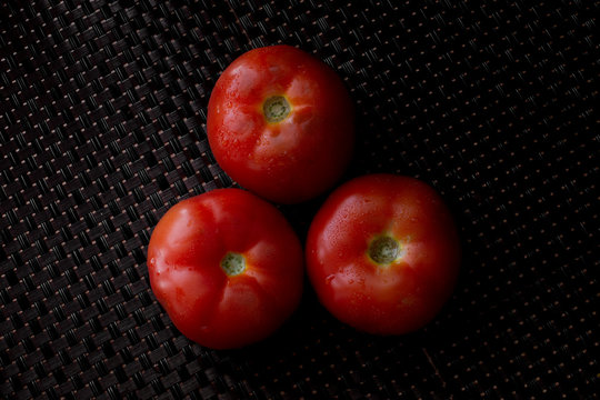 Fresh tomatoes on a plate on a dark background. a basket full of tomatoes. - Image