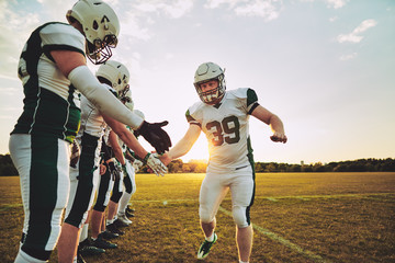 American football player low fiving his teammates after practice