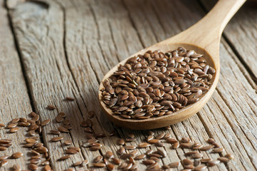 Heap of Flax seeds or linseeds in spoon on wooden backdrop. Flaxseed or linseed concept. Flax seed dietary fiber background