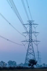 High-voltage power poles with the countryside early in the morning.