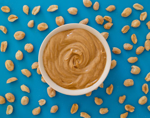 Smooth and creamy peanut butter and peanuts on blue. Top down view. © Kevin Brine