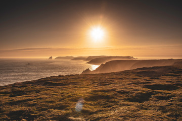 Golden hour on scenic coast of Pembrokeshire,South Wales,UK.Skomer island surrounded by mist over sea. 