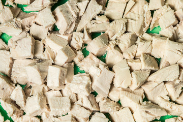 Diced boiled chicken meat on a green board