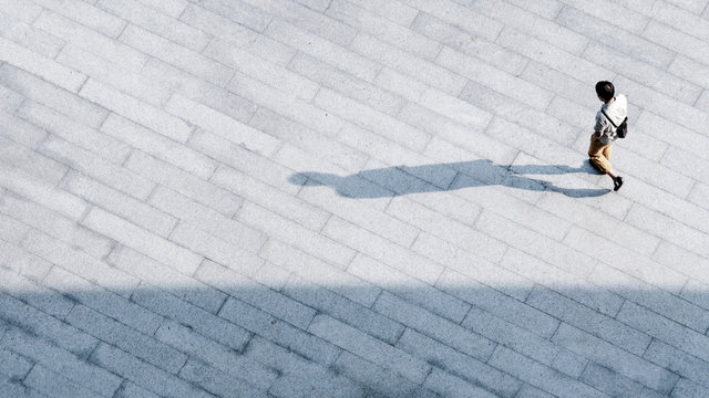 top aerial view people walk on across pedestrian concrete with black silhouette shadow on ground, concept of social still life.
