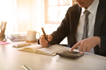 Fototapeta premium Businessman doing finances and calculate on office desk about cost at home office.