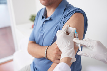 Gloved hands of doctor vaccinating patient against influenza