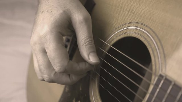 Guitar playing closeup, black and white, hand finger picking acoustic guitar