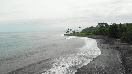 Aerial view of tropical virgin beach with black sand. Bali island, Indonesia.