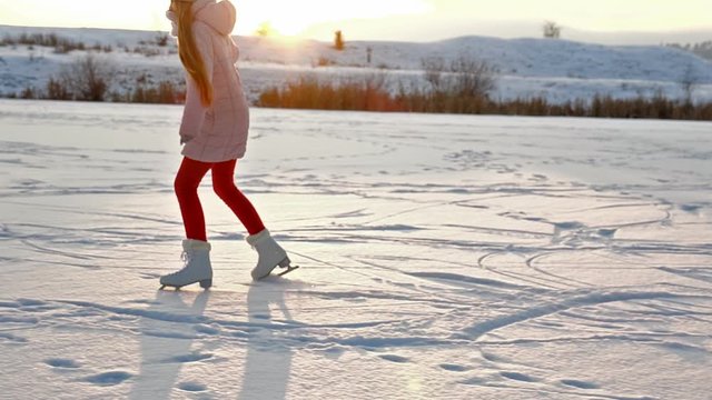 Girl ice skating on lake against setting sun - slow motion