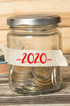 Euro Münzen und Geldscheine und Einmachglas mit dem Ersparnissen für das Jahr 2020