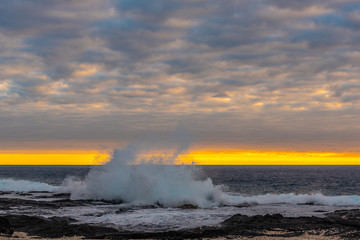 Big waves breaking onshore during sunset over ocean