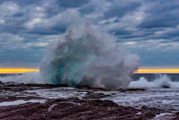 Fototapeta na wymiar Big waves breaking onshore during sunset over ocean