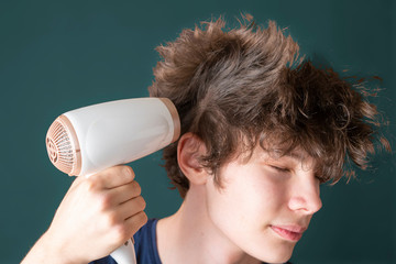 young male blow his hair with hair dryer isolated b