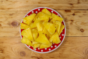 Pieces of pineapple in a plate on wooden table. Top view