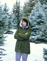 Fototapeta na wymiar Sad woman is posing in winter forest, snowy fir trees.