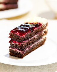 close-up of a slice of chocolate cake with cream and jam
