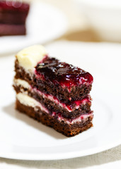 close-up of a slice of chocolate cake with cream and jam