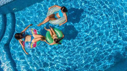 Family in swimming pool aerial drone view from above, happy mother and kids swim on inflatable ring...