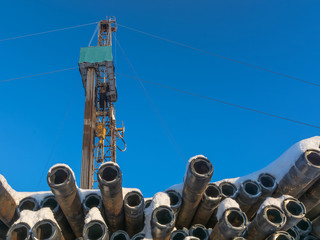 Rig for drilling for oil and gas. In the background is blue sky. Pipes covered with snow in the...