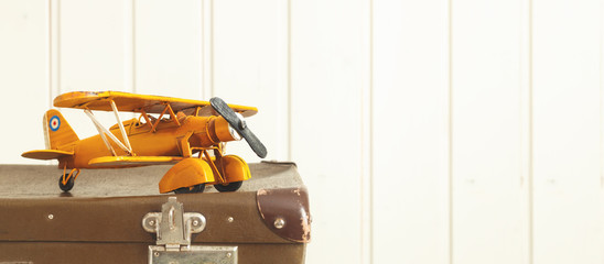 Toy yellow metal plane Old retro suitcases White wooden background Vintage tinting Copy space
