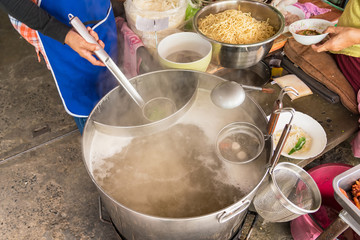 The pot is prepared for cooking. The noodles in boiling water with white smoke and steam on black background.