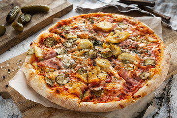 pizza with bacon and vegetables on a wooden board, closeup
