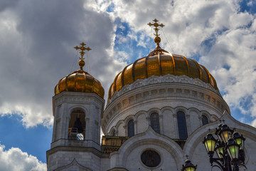 Fototapeta na wymiar Gilded dome with a cross of the Cathedral of Christ the Savior in Moscow against the blue cloudy sky