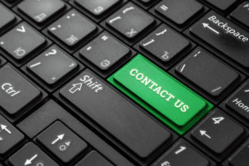 Closeup of a green button with the word contact us, on a black keyboard. Creative background, copy space. Concept magic button, communication, communication, meeting, correspondence.