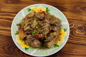 Stewed chicken liver with apple and onion on wooden table