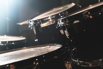 Closeup view of a drum set in a dark studio. Black drum barrels with chrome trim. The concept of live performances - obrazy, fototapety, plakaty