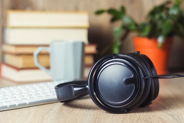 Headphones, keyboard, stack of books and cup on the office desk. Office concept, work day, hourly pay, work schedule, work in a call center