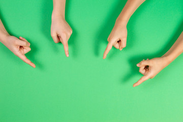 Many kids hands pointing to something on light green background