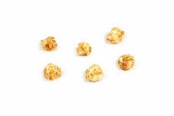Few pieces caramel popcorn on white background.