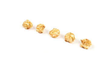 Few pieces caramel popcorn on white background.