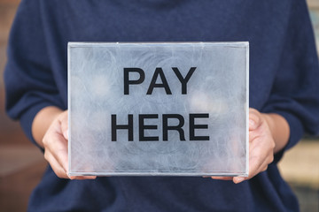 A woman holding a plastic payment box