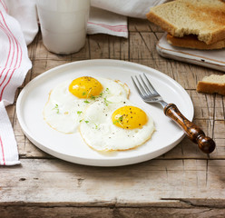 Breakfast of fried eggs, bread toasts and coffee on a wooden table. Rustic style.