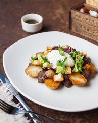 Warm salad with chicken, grilled potatoes, crackers, arugula, grated cheese and poached egg on a white plate and soy dressing. Close up. Selective focus. The concept of the menu.