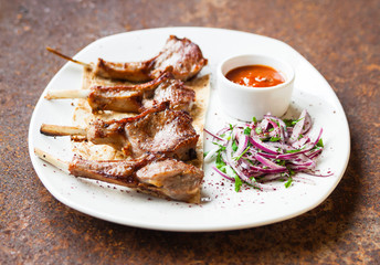 T-Bone grilled steak with fresh cabbage and red onion salad and adjika on a white plate on a stone countertop. Close up. Selective focus.