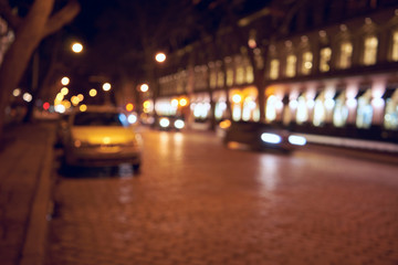 Fototapeta na wymiar Background of blurred evening road with cars and lanterns