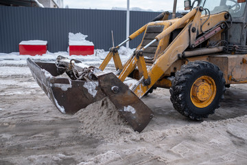 Snow removal in the city with a tractor or an excavator. Dirty snow.