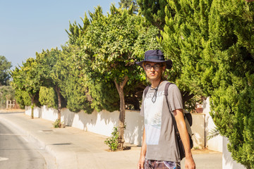 A young man in a sunhat is standing on the road in the southern town