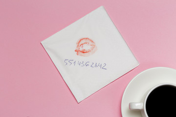 Napkin with a kiss and coffee cup on pink background.