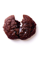 Top view image of broken soft chocolate cookie with salt flakes on white background