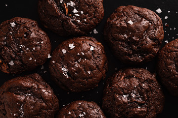 Top view image of soft chocolate cookies with salt flakes on dark background